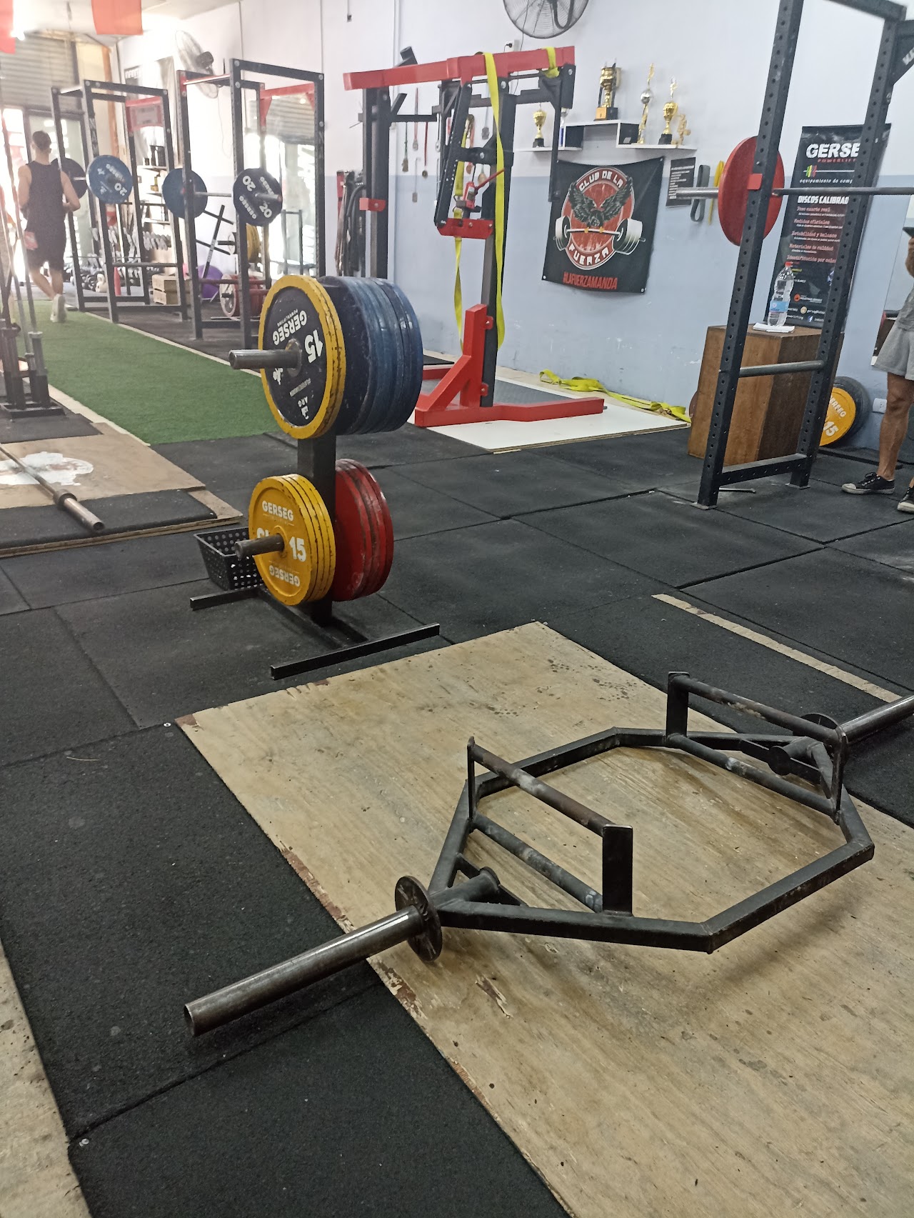 Vista interior del gimnasio con racks de potencia y discos